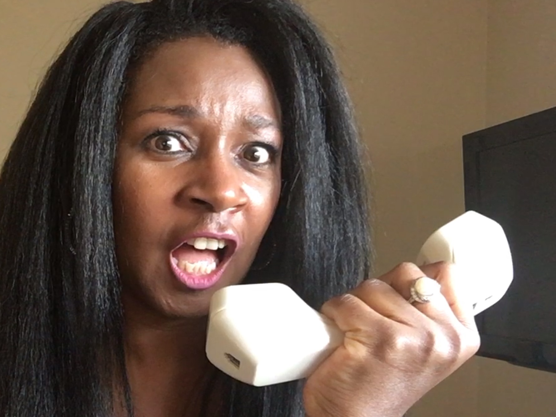 Alicia holding telephone handle up to her mouth in anger